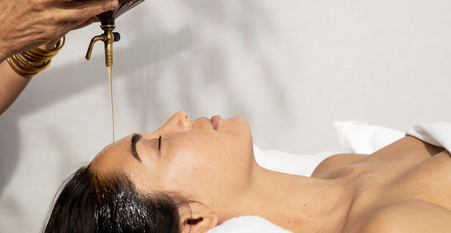 Woman with therapeutic oil being poured on her forehead and into her scalp